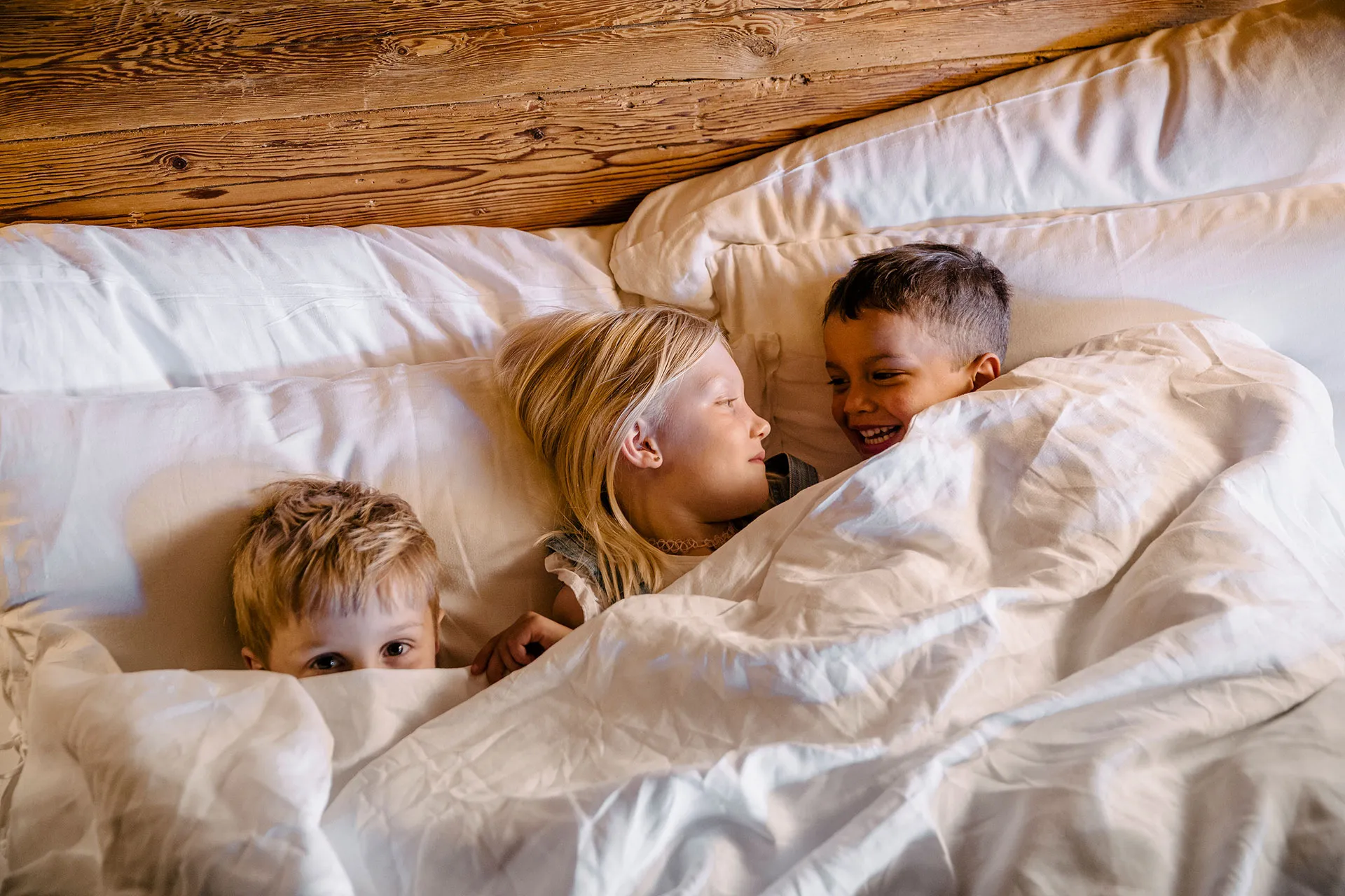 Drei Kinder kuscheln unter einer Decke